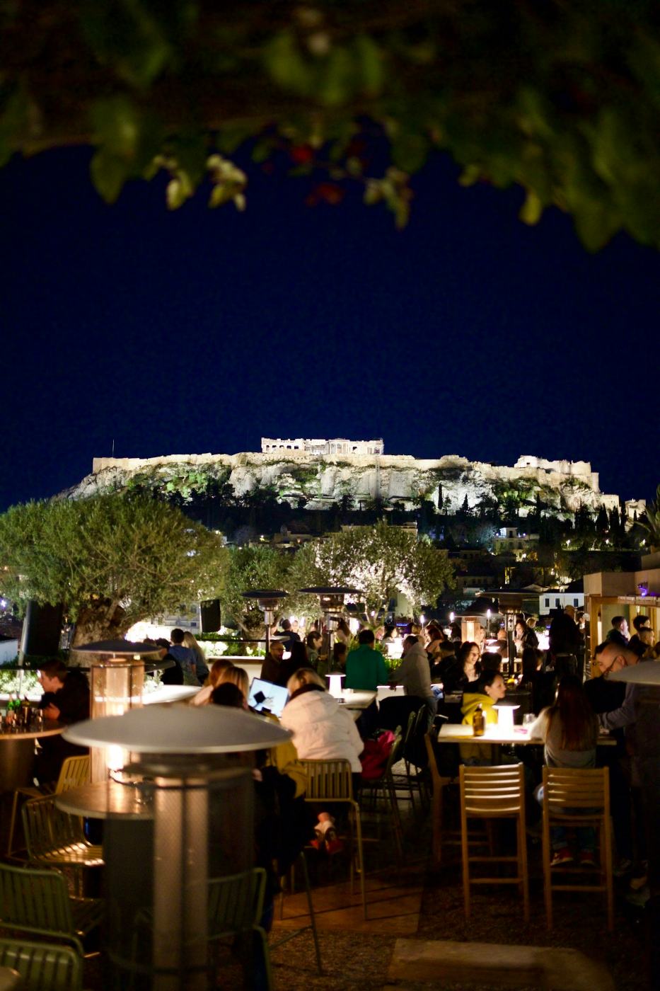 Εστιατόριο σε ταράτσα τη νύχτα, κάτω από τη φωτισμένη Ακρόπολη, στην Αθήνα