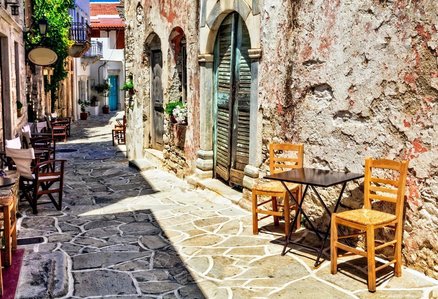 Τραπεζάκια καφενείου σε πέτρινο δρομάκι στη Χαλκί, την παλιά πρωτεύουσα της ενδοχώρας